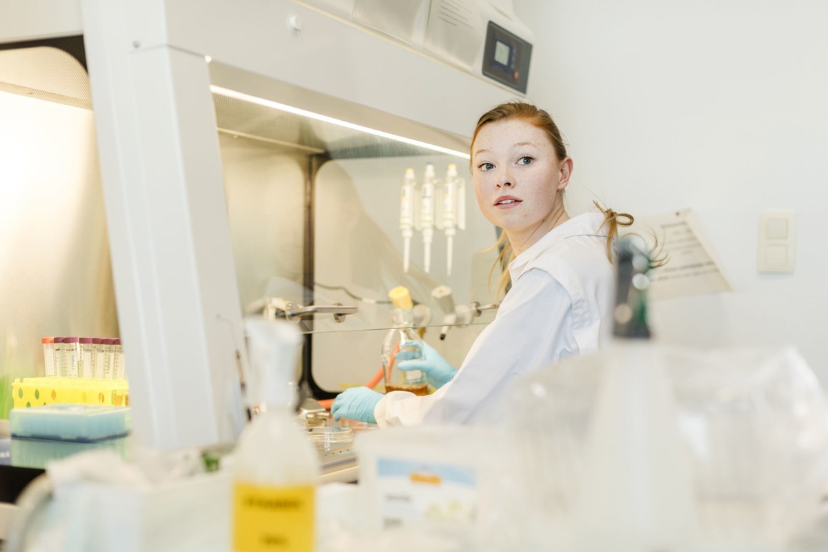 A researcher preparing samples beside laboratory equipment in a bright workspace.